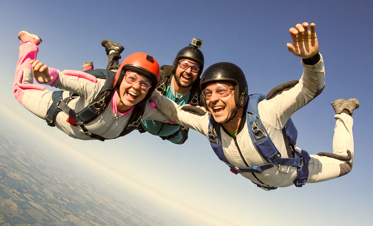 Three skydivers under an open canopy